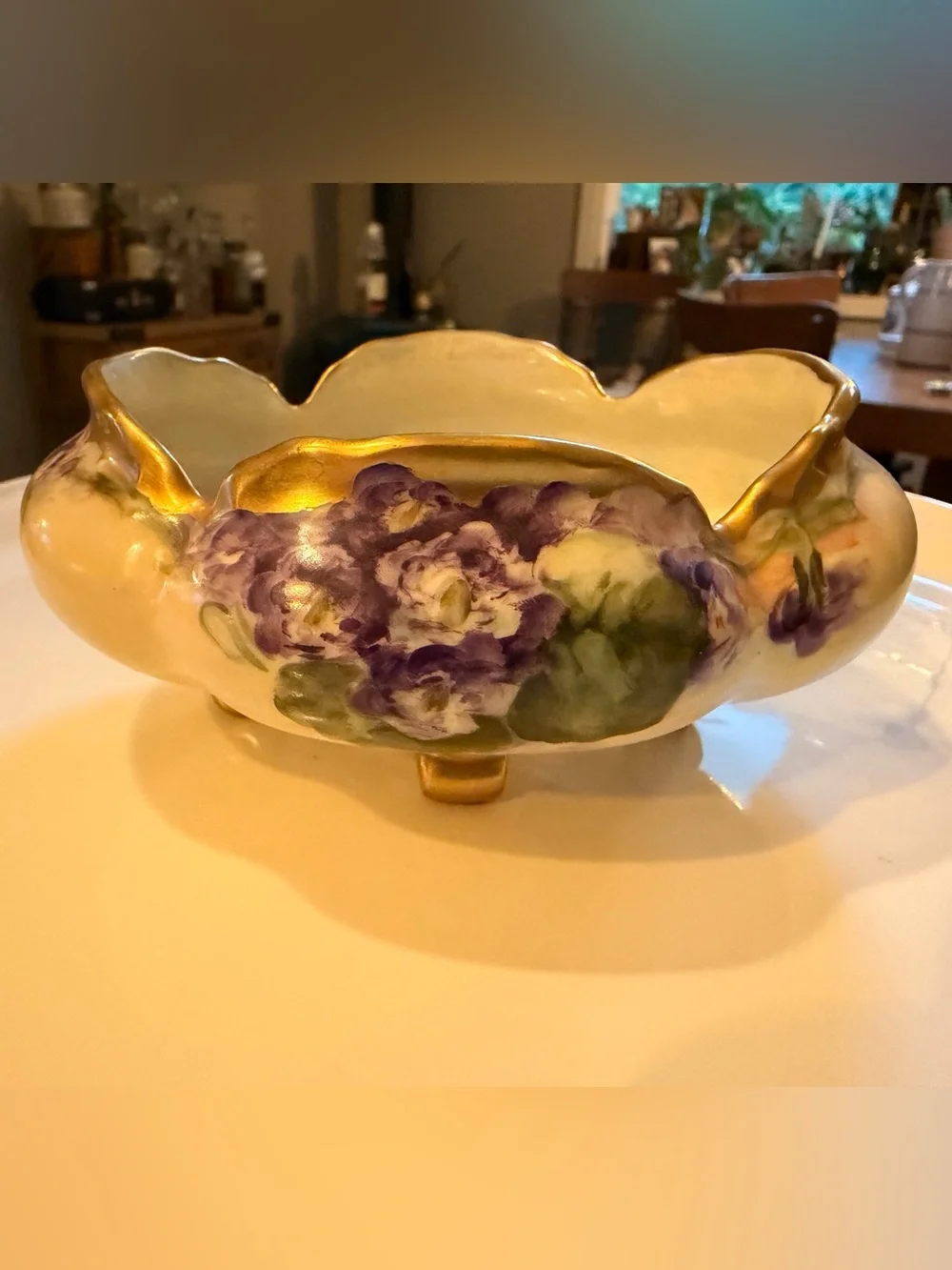 A hand-painted porcelain footed bowl with gilded rim and floral decoration.